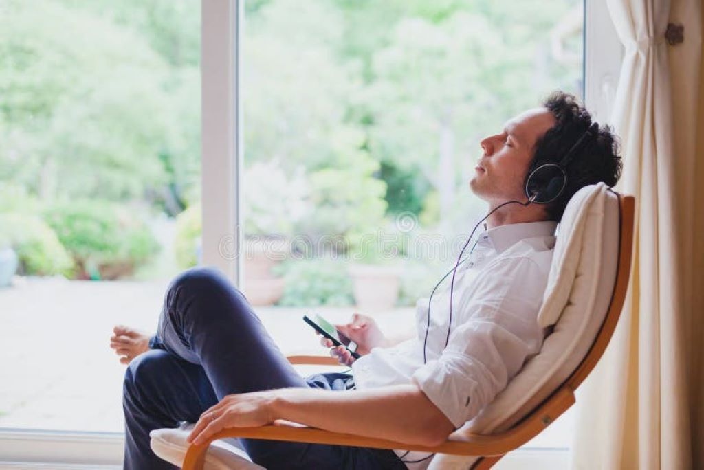 A person wearing large, open-back home headphones while sitting comfortably in a quiet room, focused on listening to music