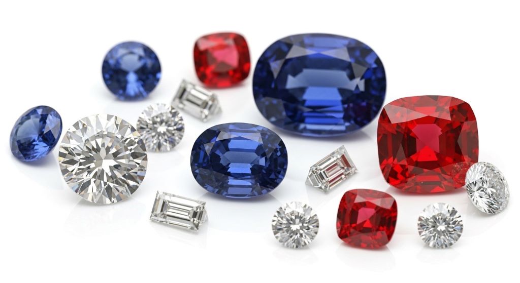 Close-up of various durable gemstones including diamond, sapphire, and ruby suitable for engagement rings on white background