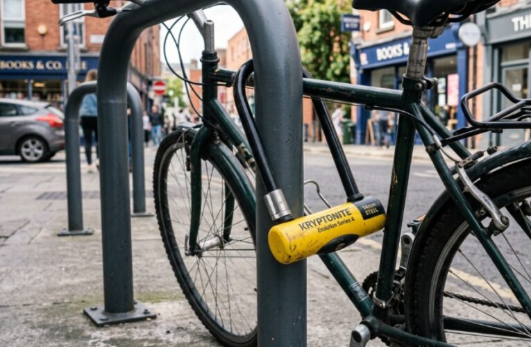 Heavy-duty yellow U-lock securing a city bicycle to a metal rack.